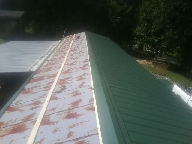 Old rusted panels beside newly installed green metal roofing — Wind Damage Roof Repair by Roofing Brothers in Marion