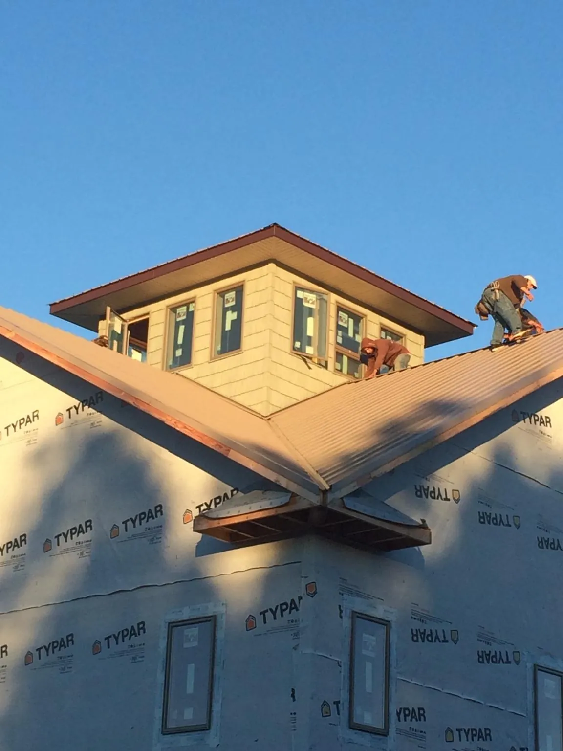 Roofers working around a rooftop cupola on a new metal roof at sunset — Roof Waterproofing in Marion by Roofing Brothers